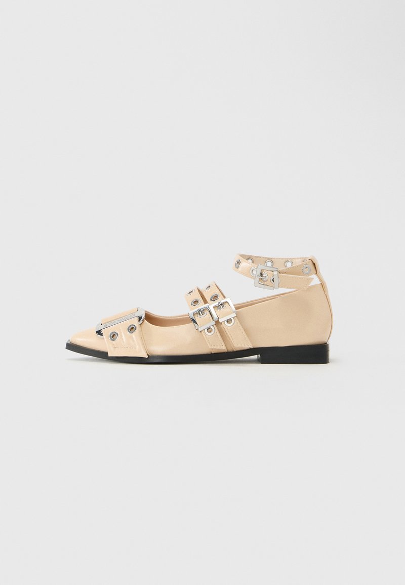 Beežid lameeritud jalanõud kitsa ninaga, kolme hõbedase pandlaga rihma ja ankle strap'iga, musta tallaga ning dekoratiivsete silmadega.