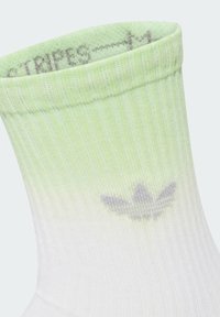 Svetlozelená a biela atletická ponožka s ribbovanou štruktúrou, ktorá má gradientný efekt a šedé logo blízko členku.