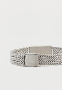 Βραχιόλι από μεταλλικό πλέγμα σε ασημί απόχρωση με ορθογώνιο κούμπωμα. Διαθέτει σχέδιο τύπου «ψαροκόκκαλο» και λείο φινίρισμα στο κούμπωμα.