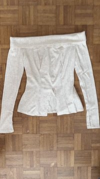 Witte geribde langwerpige top met lange mouwen en off-the-shoulder ontwerp, met een aansluitende stijl, featuring een split in het midden onder de buste en geplooide accenten.