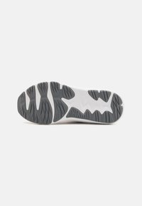 White athletic shoe sole with intricate grey traction patterns, featuring a wave-like design and textured areas for grip and flexibility.
