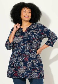Marineblaues Tunika mit floralem Muster in Rot, Blau und Beige. Verfügt über einen V-Ausschnitt und drei Viertelärmel. Weicher Stoff, lockere Passform.