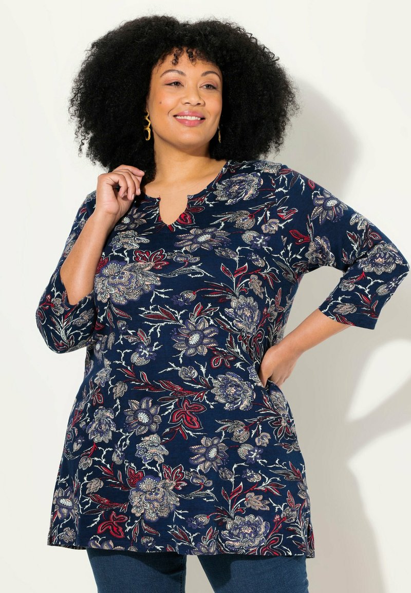 Marineblaues Tunika mit floralem Muster in Rot, Blau und Beige. Verfügt über einen V-Ausschnitt und drei Viertelärmel. Weicher Stoff, lockere Passform.