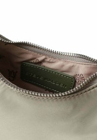 Poche zippée en tissu taupe doux avec une fermeture éclair argentée brillante. Dispose d'une étiquette verte à l'intérieur avec du texte en relief. Doublure lisse et simple.