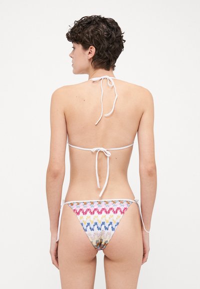 Fakó bikini színes zigzag mintával, fehér megkötőkkel a nyaknál és a csípőn, alacsony derekú kialakítással és texturált anyaggal.
