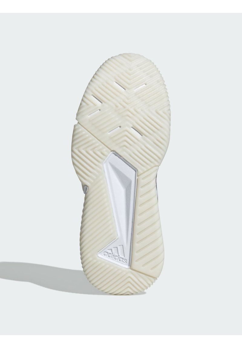 Suela de una zapatilla; presenta un patrón texturizado con líneas en zigzag, principalmente blanca con tonos crema claros; incluye un acento plateado y la marca.