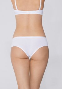 Bílé bavlněné bikini kalhotky s hladkým povrchem. Pas je elastický, s minimálním šitím a bez viditelných vzorů či kovových prvků.