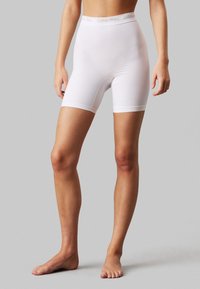 Shorts bianchi in misto cotone con una superficie liscia, dotati di un bordo vita con logo Calvin Klein e un design aderente che arriva fino a metà coscia.