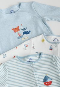 Trois bodies pour bébé avec des motifs nautiques : bleu clair avec crabe, baleine et voiliers ; blanc avec petits animaux marins et bateaux ; rayé bleu avec voilier rouge.