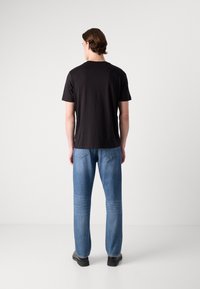 Black short-sleeve t-shirt and light blue denim jeans. The jeans have a straight fit with detailed back pockets, paired with black shoes.
