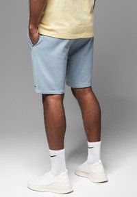 Lyseblå shorts lavet af blødt stof, med sidelommer og ribbet kant. Båret med hvide sneakers og ankelsokker med logo.