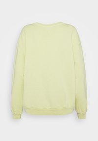 Sweat-shirt jaune clair à coupe ample, encolure ronde et poignets côtelés. Tissu uni sans motifs ni accents.