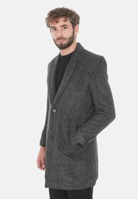 Cappotto grigio a spina di pesce con revers a punta, chiusura a singolo bottone e due tasche frontali. Tessuto testurizzato, design fino al ginocchio.