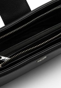 Portafoglio in pelle nera con diversi scomparti con zip, hardware in argento e una finitura testurizzata all'interno, dal design elegante e rettangolare.