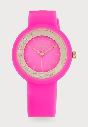 Montre en silicone rose avec un cadran rond, des accents dorés et une lunette ornée de cristaux. Elle dispose d'un cadran rose éclatant et de repères horaires dorés.