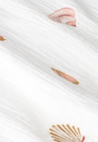 White fabric featuring embroidered seashell patterns in soft pink and gold tones, with a textured, crinkled appearance.