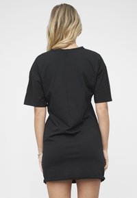 Sort, kortermet kjole med løs passform. Har rund halslinning og rette kanter, laget av mykt, lett bomullsstoff.