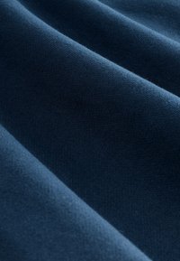 Tume sinise kangaste makro, fine kudumiste tekstuuri ja pehmete voldidega, mis tekitavad õrnu varje.