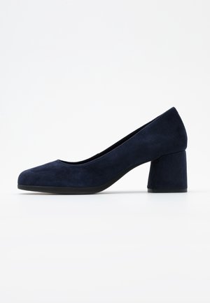 Escarpin en daim bleu marine pour femme avec un bout arrondi et un talon moyen épais sur fond blanc.