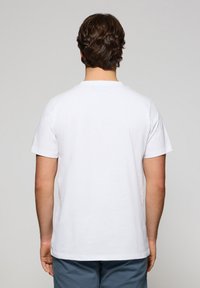 Witte katoen t-shirt met korte mouwen en een ronde halslijn, gezien vanaf de achterkant. Gladde textuur, minimalistisch ontwerp, geen zichtbare logo's.