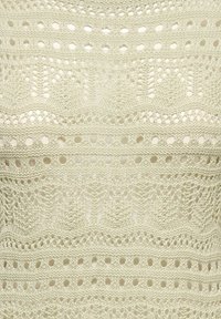Haut tricoté avec un motif à tissage ouvert, présentant des bandes alternées de grands et petits trous, dans une couleur crème claire.