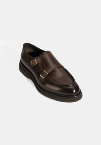 Braunelederschuhe mit doppelten Schnallen, runder Zehenform und strukturierter Sohle. Sie zeichnen sich durch ein elegantes Design und eine saubere Nahtverarbeitung aus.