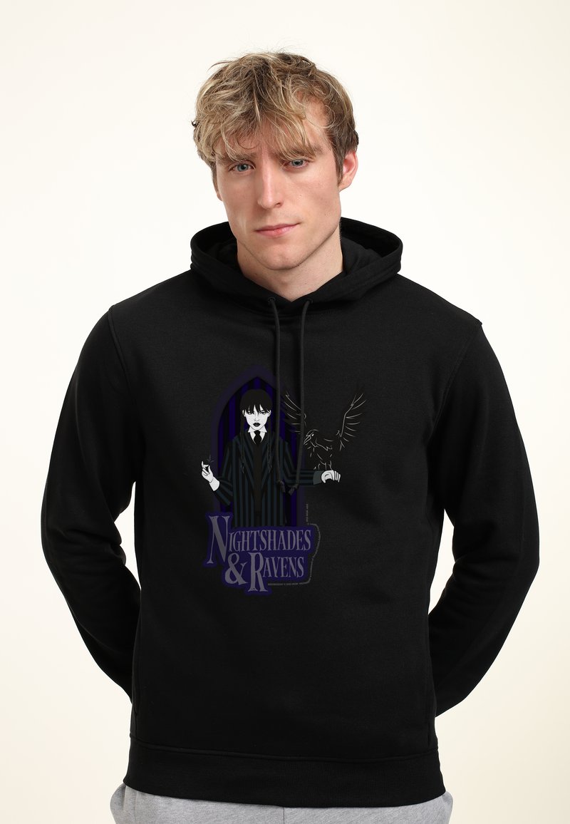 Sudadera negra con un diseño gráfico de un personaje en un traje de rayas sosteniendo un cuervo, con el texto "Sombras Nocturnas y Cuervos" debajo.