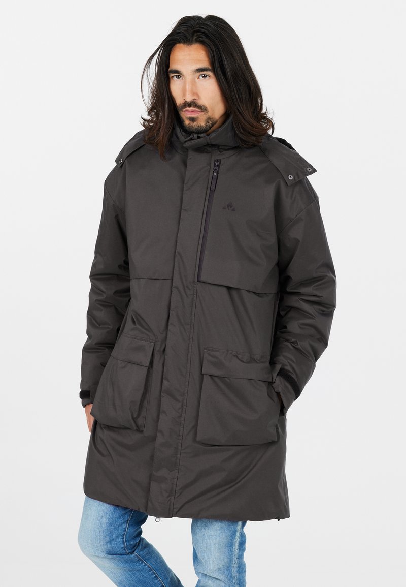 Parka gris foncé avec un devant zippé, de grandes poches avant et un col haut. Présente une capuche amovible et un tissu lisse et résistant à l'eau.