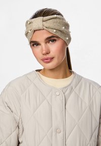 Beidzis adīts galvas variants ar mezglu dizainu, rotāts ar pērlēm un mazām dārgakmeņiem, kopā ar vieglu quilt jacket.