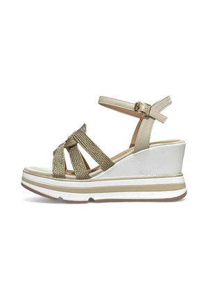 Sandalo con zeppa con suola platform bianca, cinturino beige alla caviglia con fibbia e cinturini intrecciati dorati che attraversano il piede.