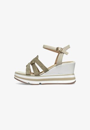 Sandalo con zeppa con suola platform bianca, cinturino beige alla caviglia con fibbia e cinturini intrecciati dorati che attraversano il piede.