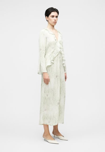 Φόρεμα ανοιχτού πράσινου χρώματος με μακριά μανίκια, διακοσμημένο με βολάν στο εμπρόσθιο μέρος και λουλουδάτα μοτίβα. Απαλό, ρέον ύφασμα με μήκος μέχρι τη μέση της γάμπας και άνετη σιλουέτα.