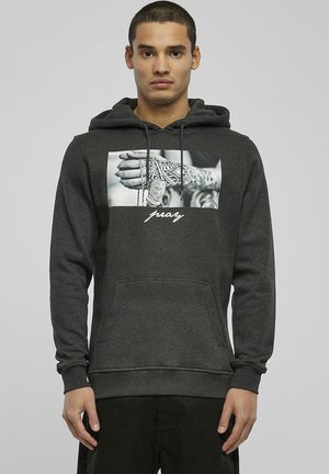 Huppari harmaasta puuvillasta, jossa on etutasku, naru-hoodie ja voimakas grafiikka tatuoidusta kädestä, jossa on koruja.