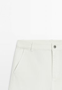 White denim pants with belt loops, front pockets, and a metal button closure on a white background.