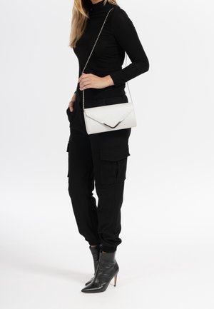 Hvid lædertaske med tekstureret overflade og spids klaplukning, med sølvkæde-rem og metalliske detaljer.