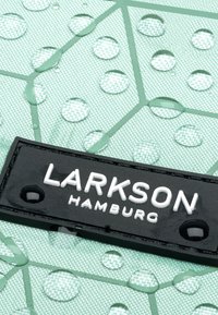 Black label with white text "LARKSON HAMBURG" on textured mint green surface with water droplets. Geometric pattern visible.