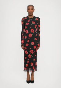 Lang, tettsittende kjole i svart gjennomsiktig stoff, med rødt blomstertrykk. Lange ermer og bølgekant, kombinert med svarte spisse hæler.