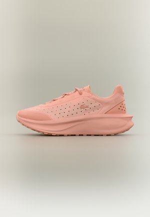 Baskets de sport rose clair avec panneau latéral perforé, semelle épaisse, et logo subtil affiché sur un fond neutre.