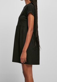 Krátké černé bavlněné šaty s krátkými rukávy, řaseným pasem a volným střihem, s kulatým výstřihem a hladkou texturou.