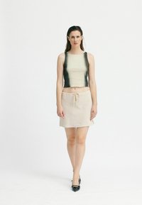 Lätt designad crop top i beige med en gradient svart nederkant. Matchad med en knäd length linne kjol i creme, med dragsko i midjan.