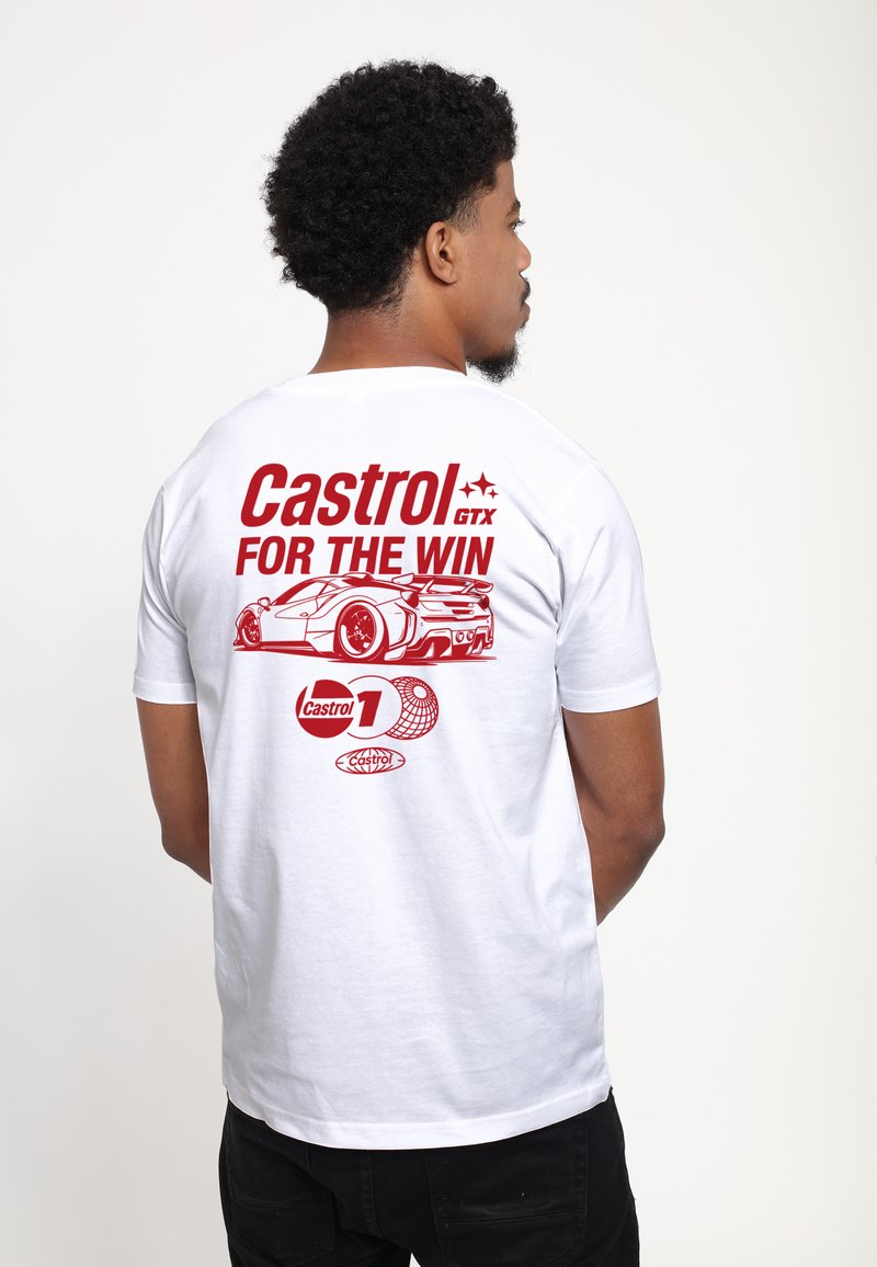 Mand iført hvid T-shirt med rød tekst "Castrol GTX FOR THE WIN" og racerbilsillustration på ryggen, stående mod en ensfarvet baggrund.