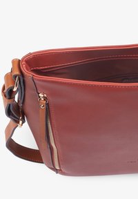 Bolso de cuero marrón con una textura suave, que presenta un bolsillo con cremallera y una correa de hombro con acentos en contraste en tono canela y azul marino.