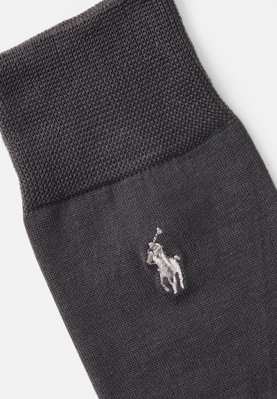 Calcetín de algodón gris oscuro con un puño texturizado y un pequeño logotipo bordado de un caballo y jinete. Cuerpo liso con un tejido uniforme.