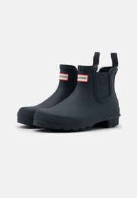 Bottes en caoutchouc bleu marin avec une finition mate. Équipées de panneaux latéraux élastiques, de tirants et d'une semelle texturée pour une meilleure adhérence.
