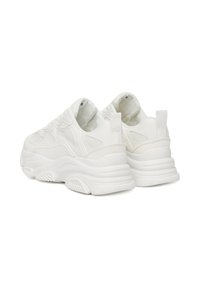 Pár robustních bílých tenisek s tlustými podrážkami, síťovanými a koženými detaily, z pohledu zezadu na bílém pozadí.