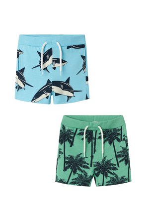 Blaue Badeshorts mit Haifischmotiven und weißem Kordelzug. Grüne Badeshorts mit Palmenmuster und passendem Kordelzug. Zwei Stile.
