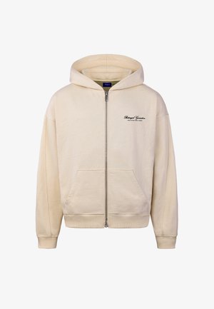 Beiger Reißverschluss-Hoodie mit Fronttaschen, gerippten Bündchen und schwarzem Schriftzug "Betrayed Generation" auf der linken Brust.