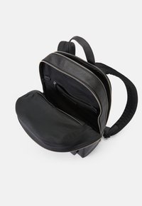 Mochila preta com um exterior texturizado, compartimentos duplos com fecho éclair e um interior de tecido suave com bolsos para organização.