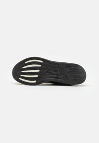 Black athletic shoe sole with a textured rubber surface. Features curved indentations and white accents for traction and design detail.
