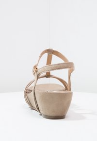 Sandale à plateforme beige avec une texture en daim doux, une bride de cheville réglable et un bout arrondi. Dispose d'un talon robuste et d'un design minimaliste.